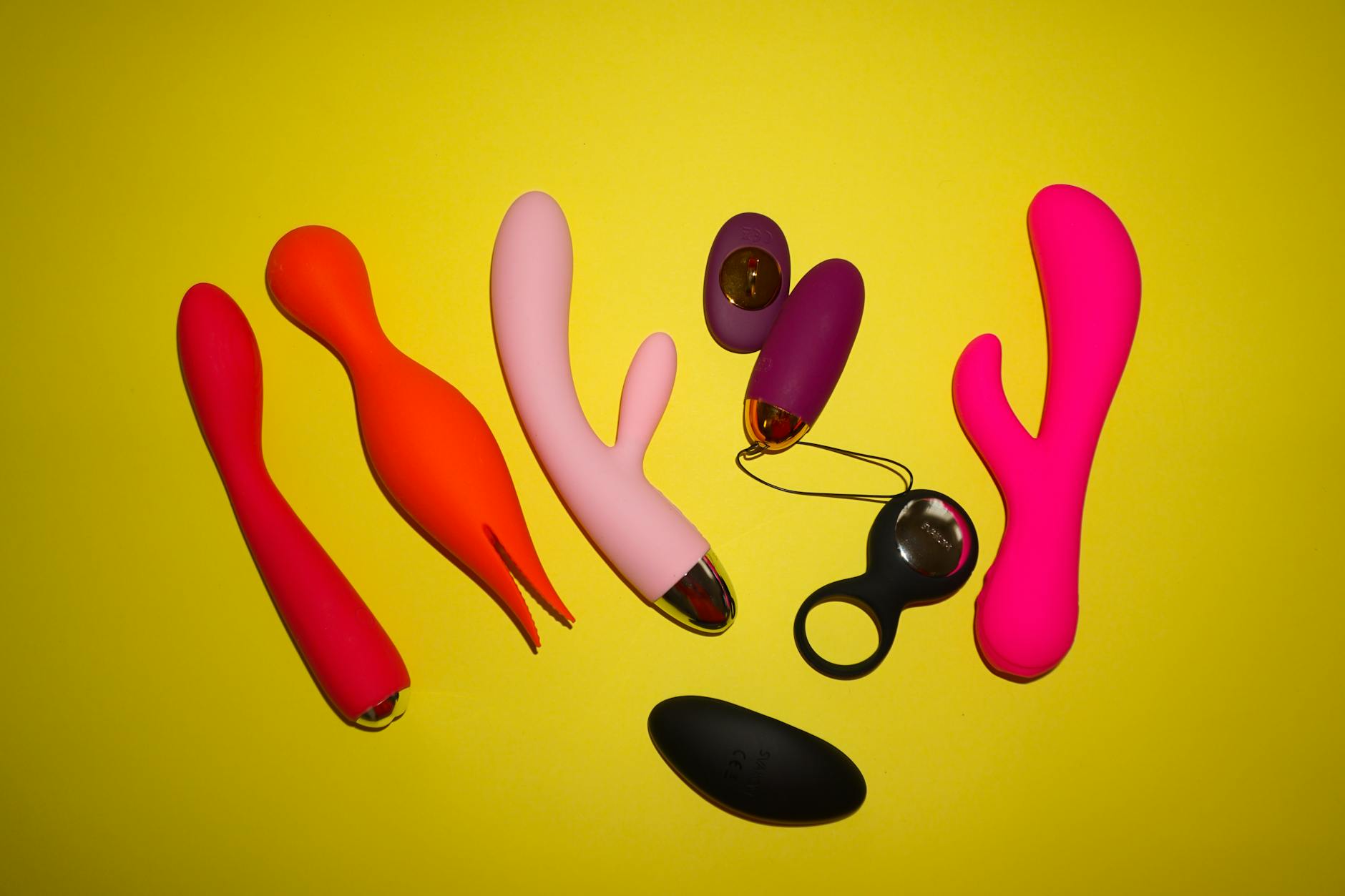 Colorful lemon vibrators and adult toys displayed on a bright yellow surface showing design diversity